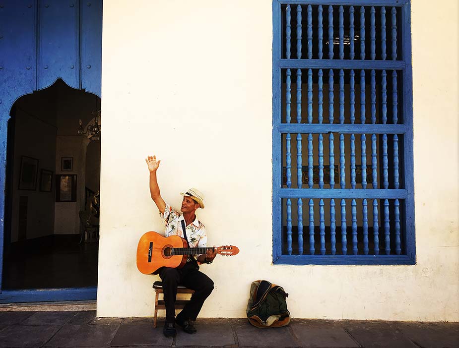 Een inwoner in Cuba met gitaar voor een gebouw