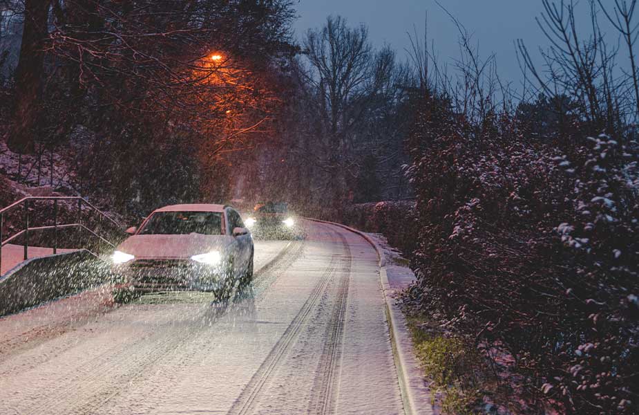 Auto op de weg in de avond op besneeuwde weg