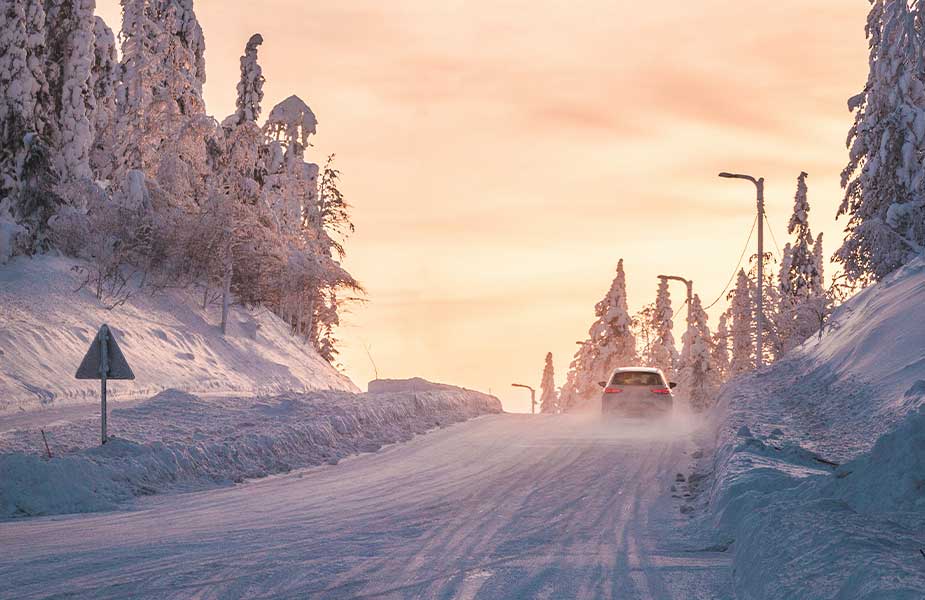 Rijdende auto in sneeuw bij zonsopkomst