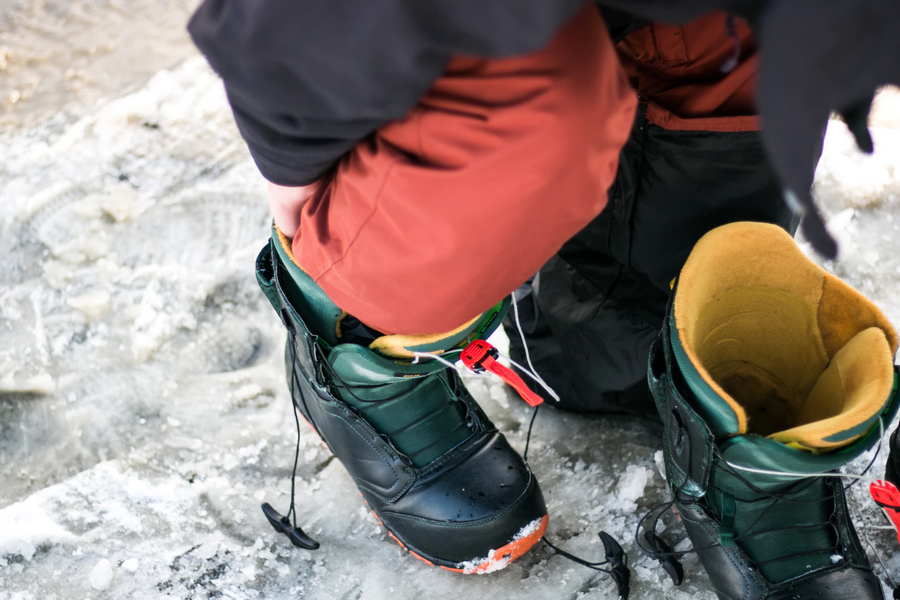 Snowboard schoenen aantrekken op wintersport.