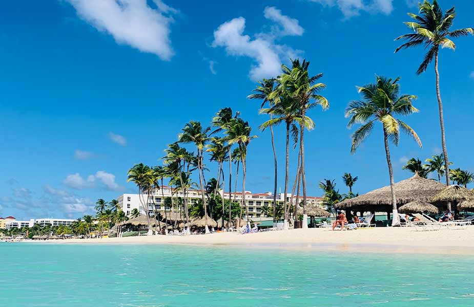 Strand op Aruba met blauwe zee en palmbomen