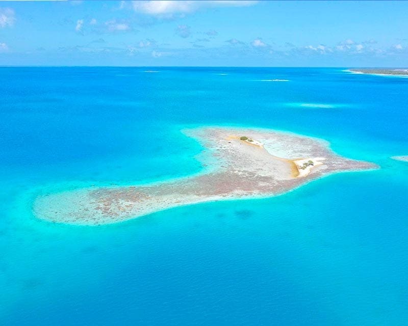 Eilandje en blauwe zee Tuamotu archipel 