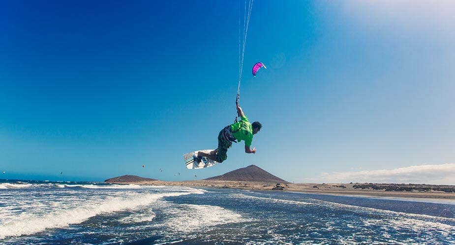 Een kitesurfer vliegt over het water bij El Medano