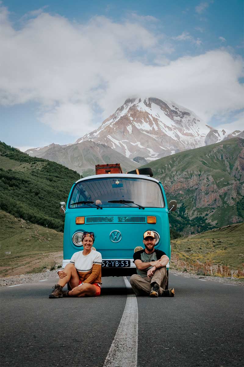 Milene en Yuri voor de bus met op de achtergrond bergen