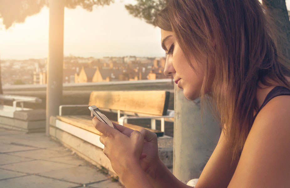 Vrouw op een bankje met een telefoon in de hand